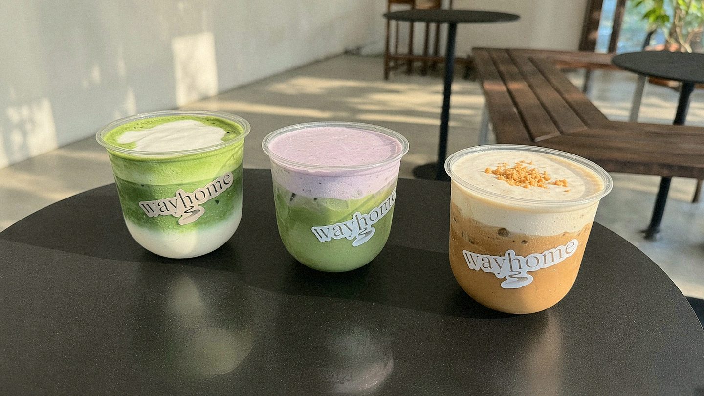 Three signature drinks on a black table: matcha latte, blueberry duo matcha, and sweet potato einspänner.