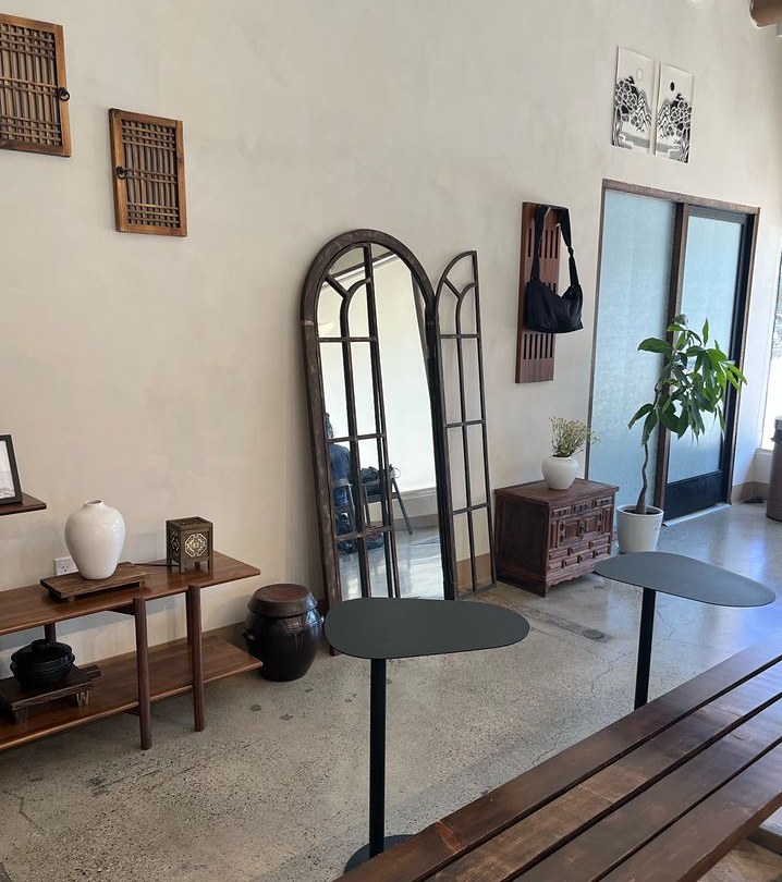 Arched wooden mirrors, benches and black round tables.