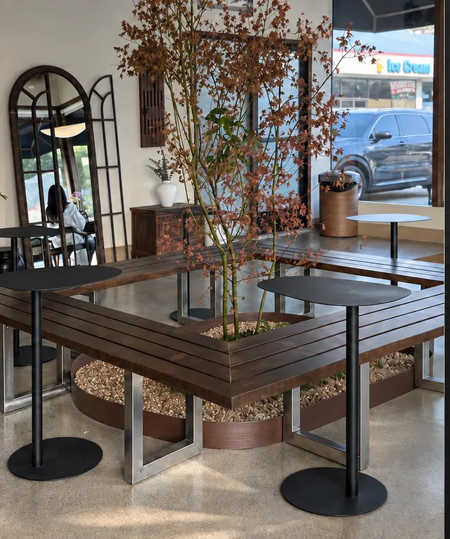The slender tree growing through the walnut bench inside the cafe, with arched mirrors behind.